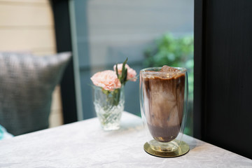 Iced mocha - A glass of coffee latte mixed with black cocoa on wooden table and blurred background, Perfect for breakfast time.