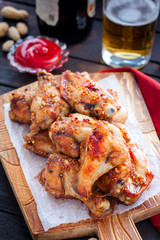Baked beer wings on a wooden board, selective focus