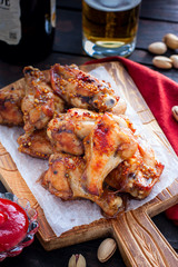Baked beer wings on a wooden board, selective focus