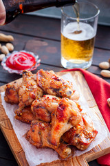 Baked beer wings on a wooden board, selective focus