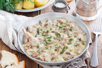 Forest mushrooms in sour cream sauce on a pan on a wooden table, horizontal