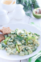 Salad with cucumbers, egg and avocado on a white plate, selective focus