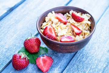 Fresh homemade muesli, muesli with strawberries in a plate on a blue background