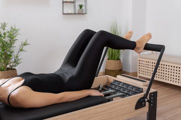 Young woman exercising on pilates reformer bed
