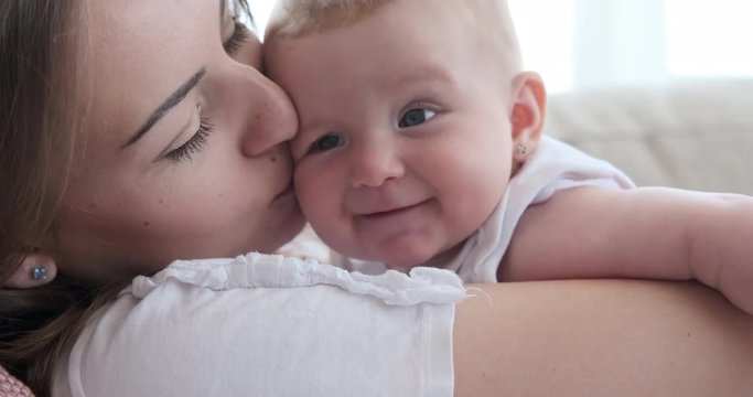 Happy woman kissing her cute baby daughter at home