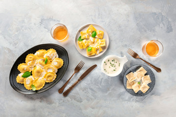 Italian Food. An assortment of various ravioli, shot from the top with a sauce, glasses of white wine, and copy space