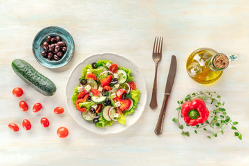 Fototapeta na wymiar Greek salad with ingredients. An overhead photo of a plate of fresh salad with lettuce, feta cheese, tomatoes, cucumbers, onions and olives, with a place for text