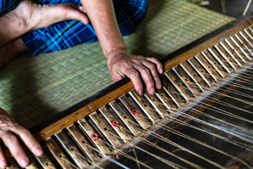 Close-up on the hands of an old woman weaving sedge mat in Ben Tre, Mekong delta region, Vietnam.