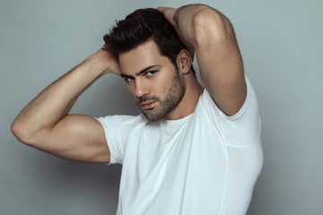 Muscle strong beautiful stripped male model in denim blue jeans with white t-shirt on grey isolated font background