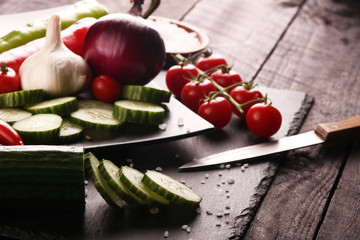 Healthy food. Vegetables on a black plate and stone cutting board and wooden background.