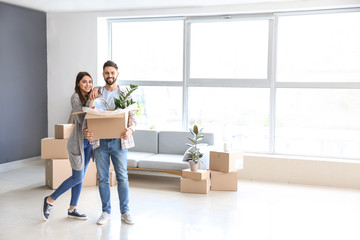 Young couple with belongings in their new house - obrazy, fototapety, plakaty