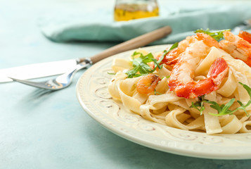Plate with tasty shrimps and pasta on table