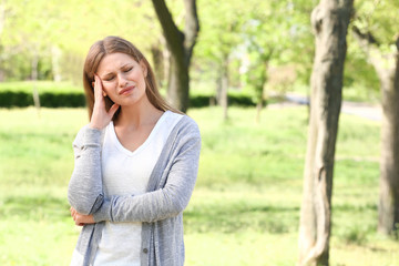 Young woman suffering from headache outdoors