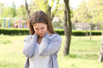 Young woman suffering from neck pain outdoors