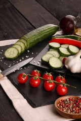 Healthy food. Vegetables on a black plate and stone cutting board and wooden background.