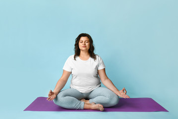 Beautiful plus size woman meditating on color background. Concept of body positive