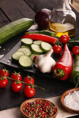 Healthy food. Vegetables on a black plate and stone cutting board and wooden background.