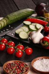 Healthy food. Vegetables on a black plate and stone cutting board and wooden background.