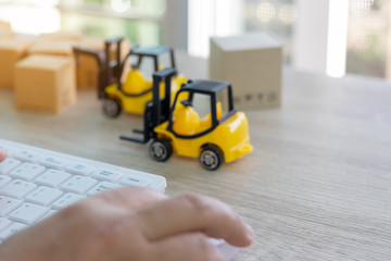 Hand using mouse and keyboard and stack of boxes and mini forklift truck nearby. Consumer can buy product directly anywhere anytime from seller using web browser. Online shopping and ecommerce concept