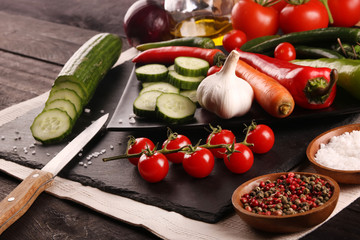 Healthy food. Vegetables on a black plate and stone cutting board and wooden background.