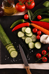 Healthy food. Vegetables on a black plate and stone cutting board and wooden background.