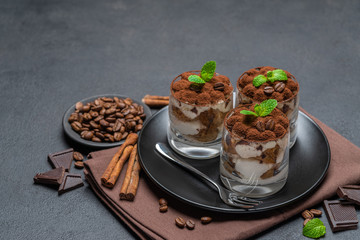 Classic tiramisu dessert in a glass on dark concrete background