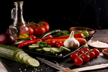 Healthy food. Vegetables on a black plate and stone cutting board and wooden background.