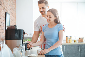 Young couple using coffee machine in kitchen