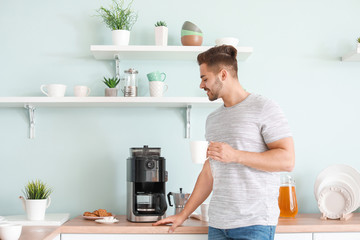 Handsome man using coffee machine in kitchen