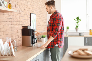 Handsome man using coffee machine in kitchen