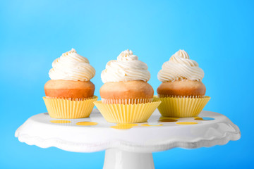 Stand with tasty Birthday cupcakes on color background