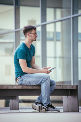 Student using a tablet pc on the campus. Outdoors, urban feeling, summertime