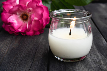 Rose and burning candle on an old wooden board. Flower frame.