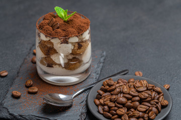 Classic tiramisu dessert in a glass on stone serving board on dark concrete background