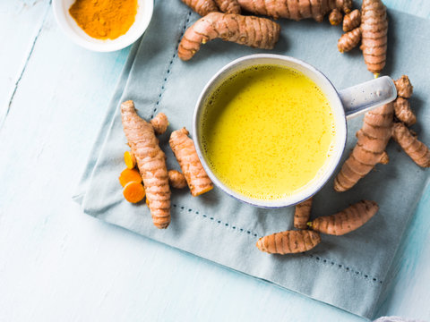 Golden turmeric coconut milk drink in mug on pastel background. Healthy remedy for sour throat and inflammation