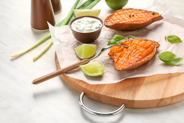 Board with tasty cooked sweet potato and sauce on table