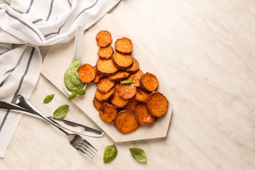 Board with tasty cooked sweet potato and sauce on table