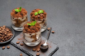 Classic tiramisu dessert in a glass on stone serving board on dark concrete background