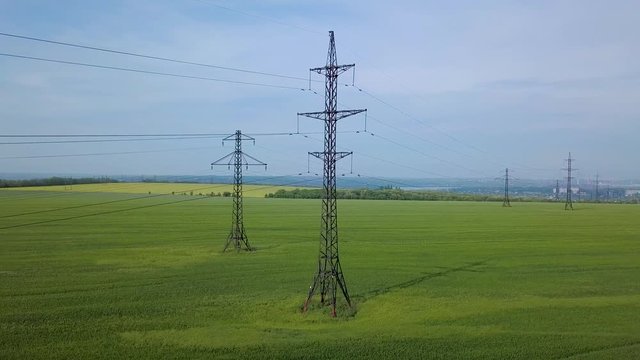 Aerial View of Electricity pylons on the green field. Fuel and power generation. 4K