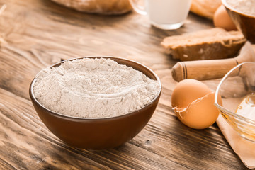 Bowl with flour on wooden table