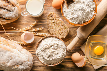Flour with products and bread on wooden background