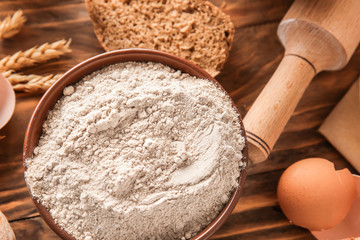 Bowl with flour on wooden table