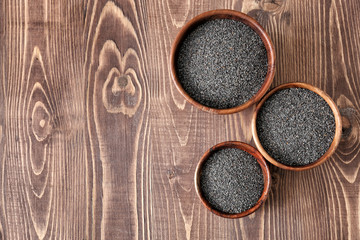 Fototapeta na wymiar Bowls with poppy seeds on wooden table