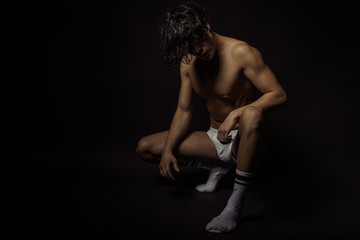 Strong stripped muscle male model in white underwear on black isolated font background