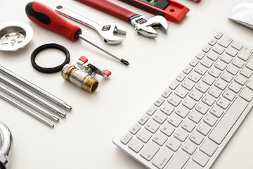 Computer keyboard and plumbing items on white background