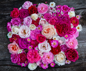 pink,red, violet and white roses on wooden surface