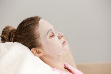 Obraz na płótnie Canvas Young woman with sheet facial mask at home