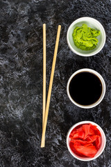 Fototapeta na wymiar Set for sushi soy sauce ginger wasabi with chopstick on stone background