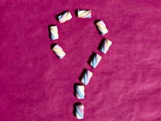 Question mark made of marshmallows on pink background. Question concept. Close-up