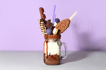 Mason jar with delicious freak shake on table